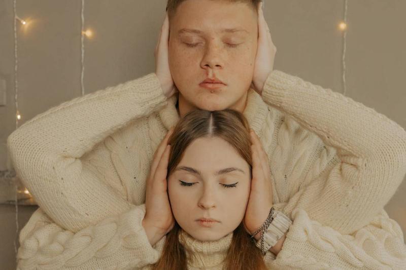 man and woman hide each other's ear with their arms intertwined