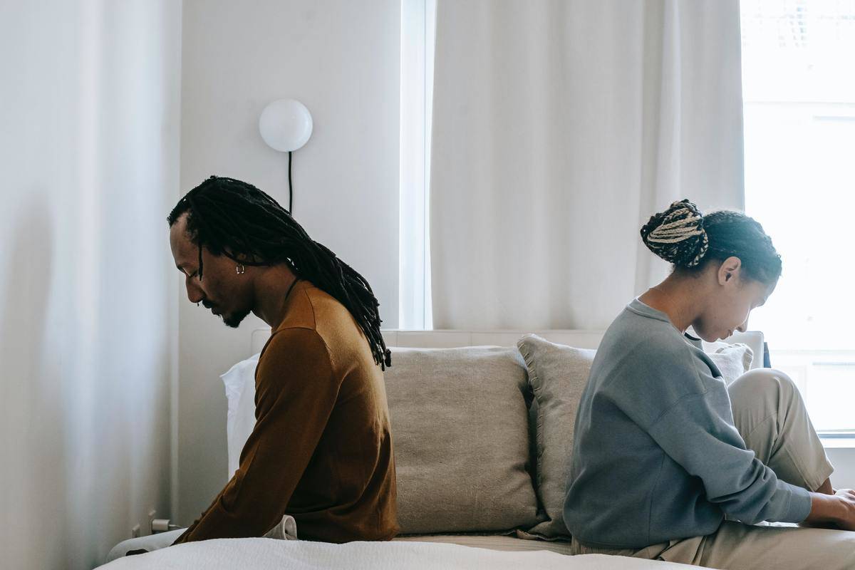 concerned-black-couple-sitting-on-bed-in-misunderstanding
