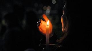 woman holding candle at night and protecting the flame with her hand