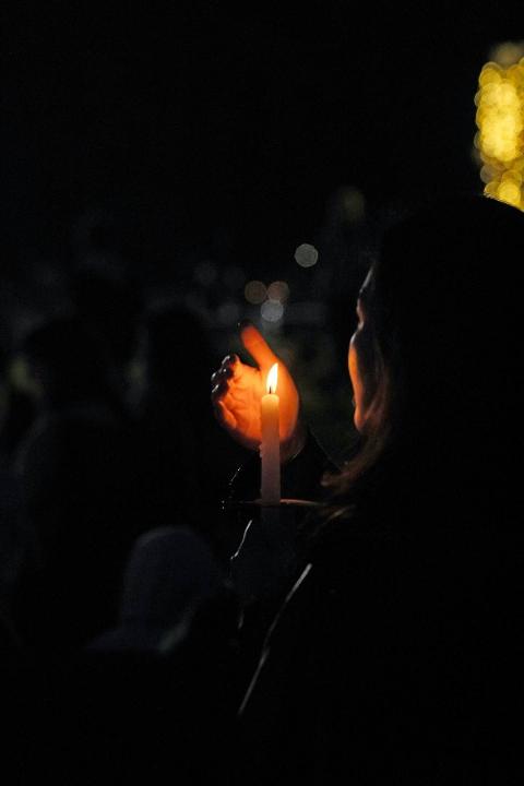 woman holding candle at night and protecting the flame with her hand
