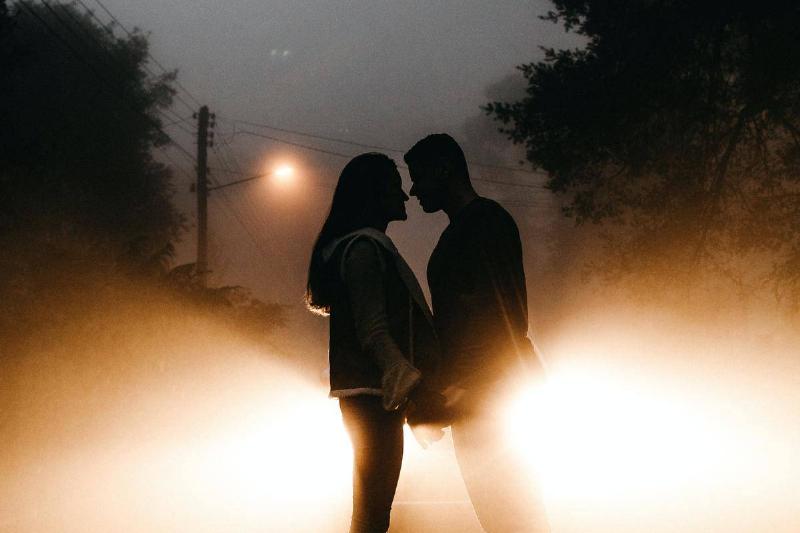hoto-of-couple-standing-on-road by lights in silhouette