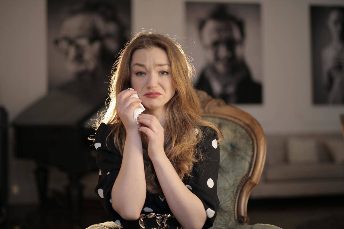 a-sad-woman-in-black-and-white-polka-dots-crying on chair