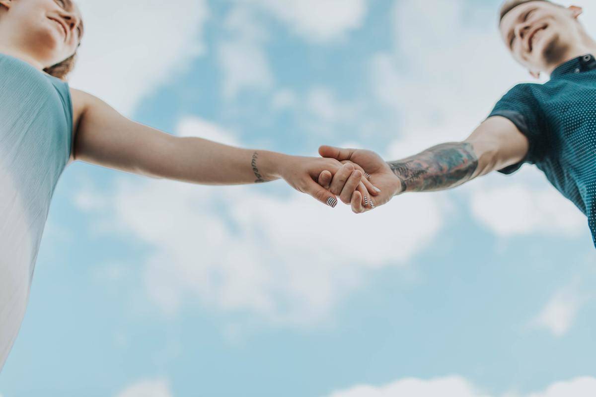 couple-holding-each-others-hands under blue sky