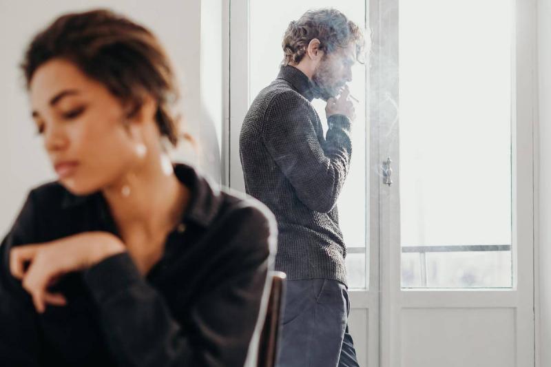 couple-having-a-misunderstanding by balcony while man smokes