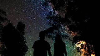Silhouettes of couple holding hands standing under the stars 