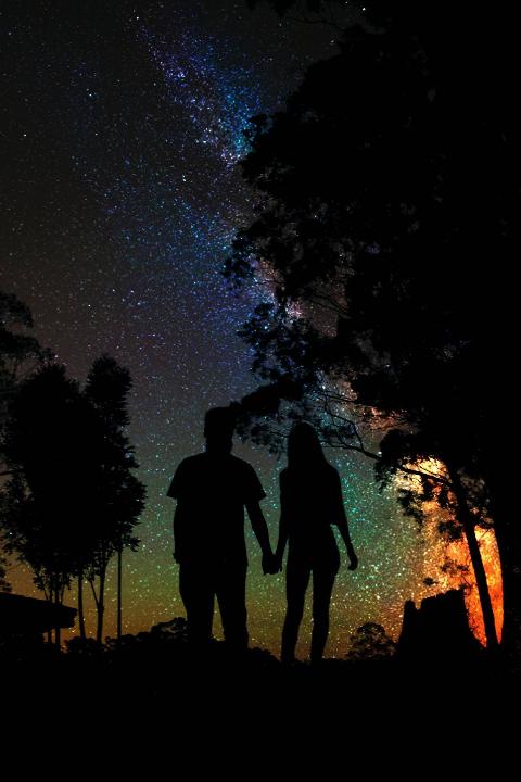Silhouettes of couple holding hands standing under the stars 