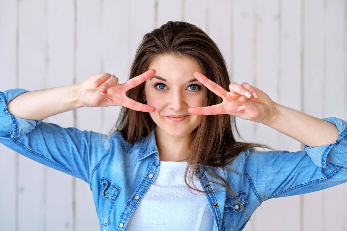 woman making peace signs by her eyes