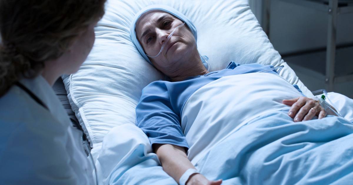 cancer patient in hospital bed looking at doctor