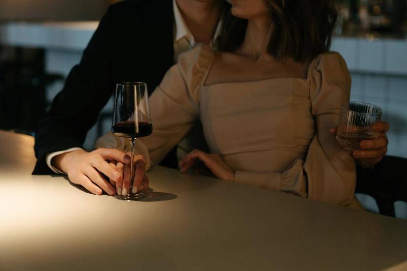 woman-in-beige-long-sleeve-shirt-holding-wine-glass- at bar with man holding her
