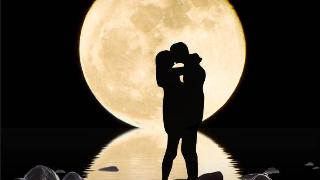 silhouette of couple embrace  standing on a rock under giant yellow moon