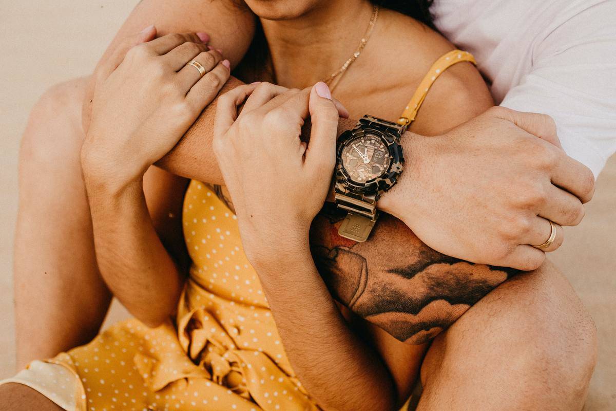 man hugs woman in from behind while sitting