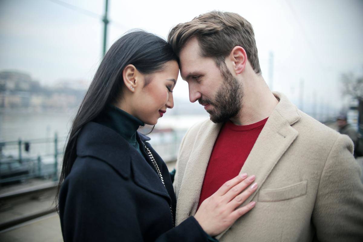 happy-multiracial-couple-hugging-on-waterfront-while-having-romantic-date-in-city-