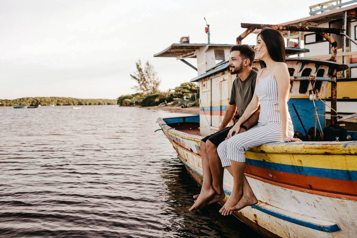 joyful-couple-sitting-on-old-boat-and-holding-hands