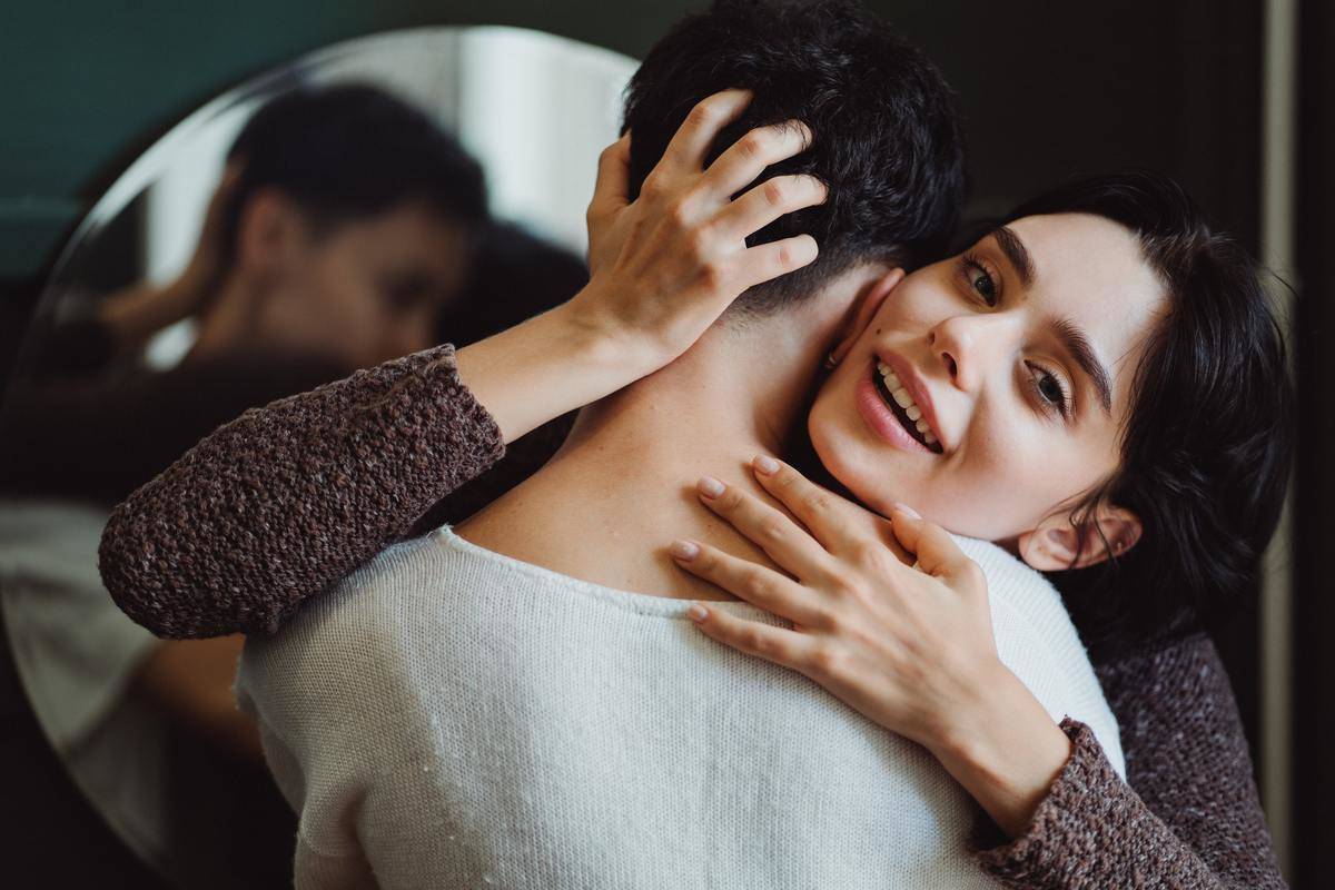 woman hugging man by mirror and smiling