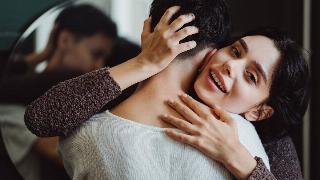 woman hugging man by mirror and smiling