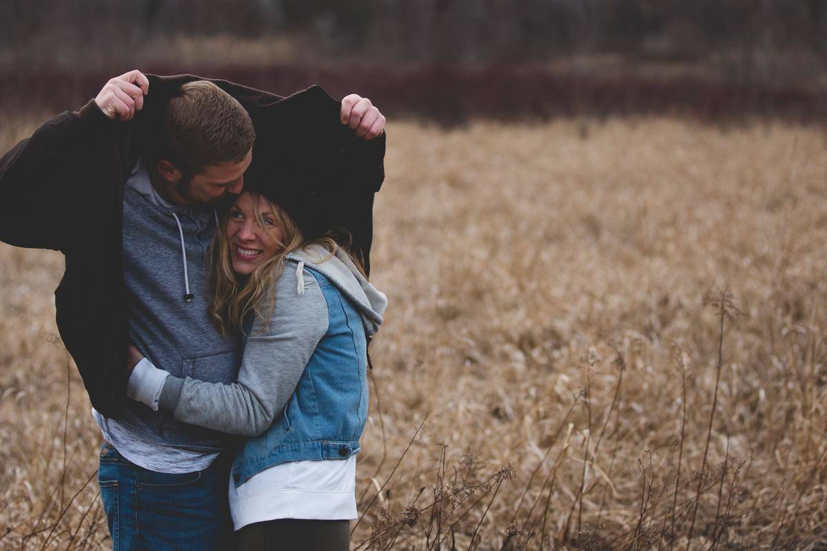 man-and-woman-hugging-on-brown-field under his jacket