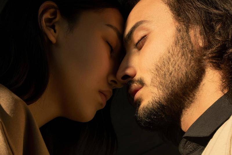 close-up-photo-of-couple-with-their-eyes-closed-facing-each-other-in-front-of-dark-background