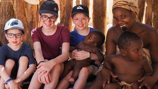 kids in hut with black woman and her babies all smile