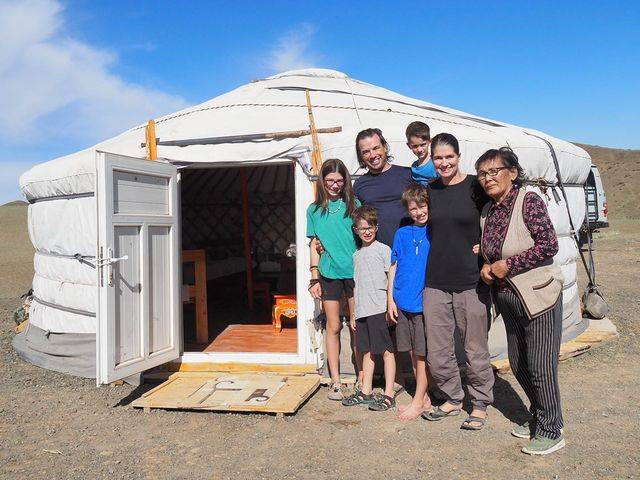 kids pose beside hut with their parents and guide