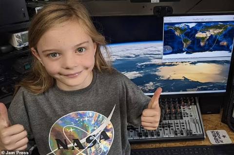 little girl gives thumbs up by space computer station