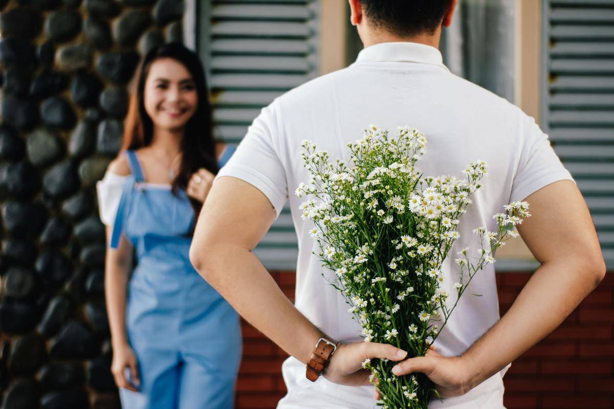 an-holding-baby-s-breath-flower-in-front-of-woman-standing-near-marble-wall-