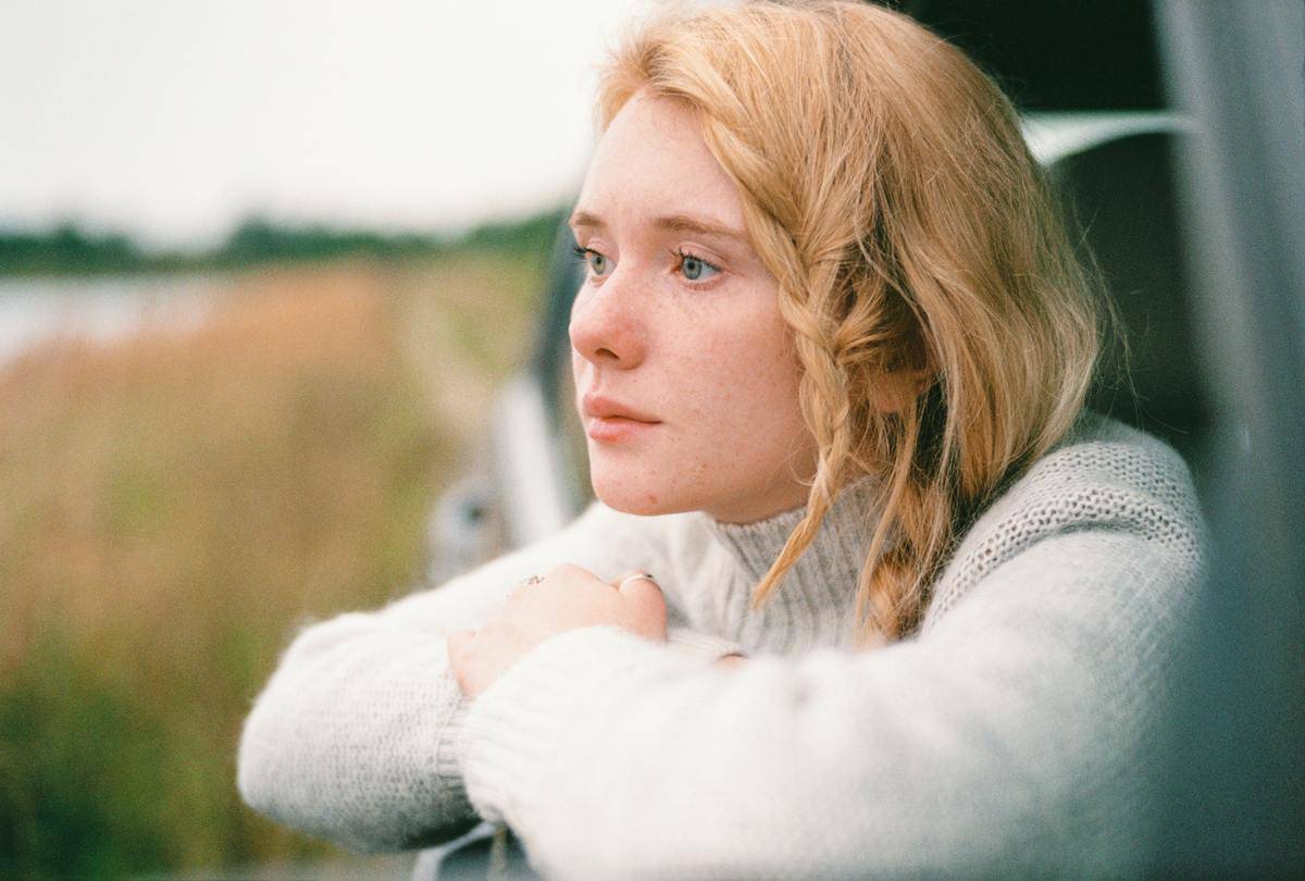 woman-in-white-sweater-thinking while looking out car widow