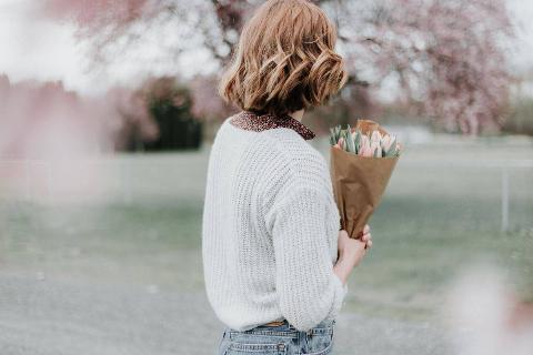 woman holding flower bouquet at the park facing back
