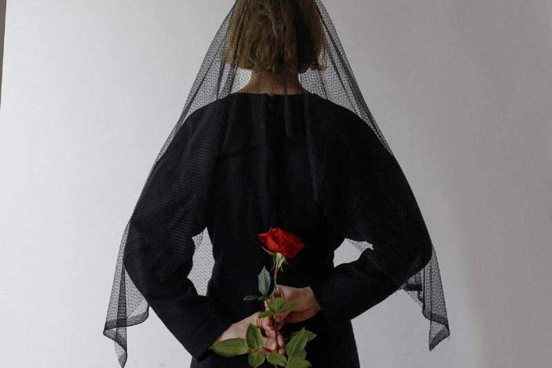 woman in black funeral clothes holding roses