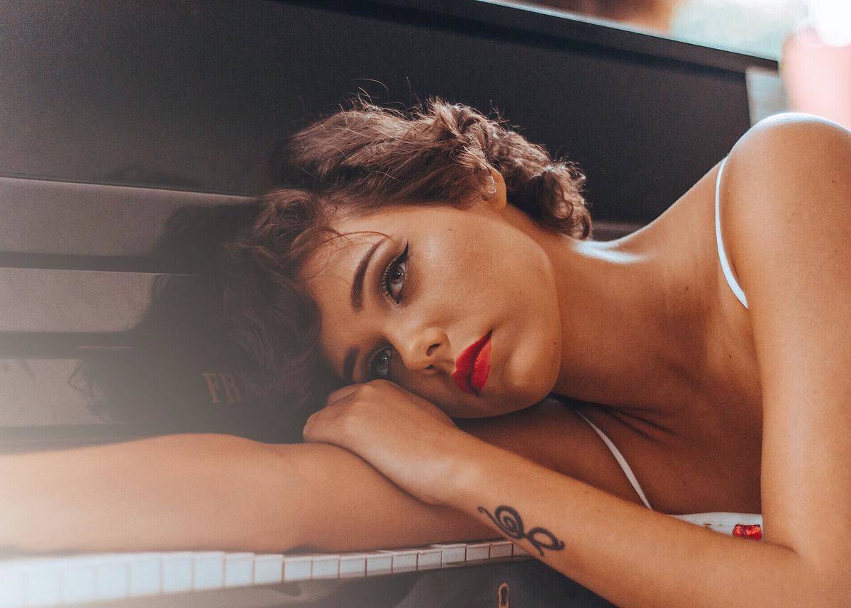 woman with red lipstick sad, laying on piano