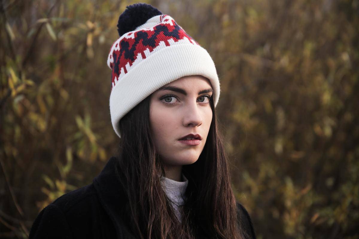 woman starring at camera with anger in a field with hat on 