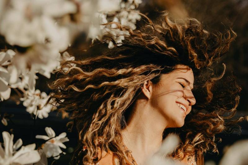 happy-woman-with-curly-hair-near-flowers
