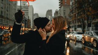 Couple stands under umbrella in the street