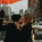 Couple stands under umbrella in the street