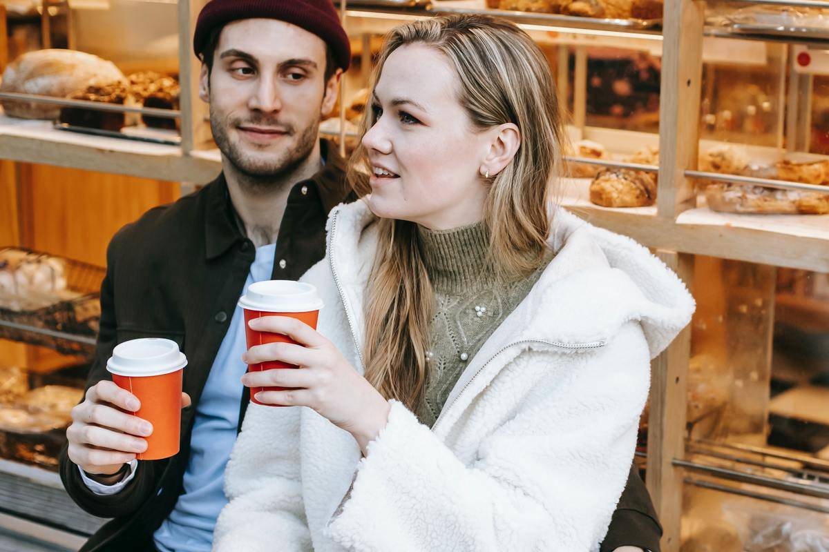 smiling-young-couple-talking-in-cafe-drinking-coffee-together