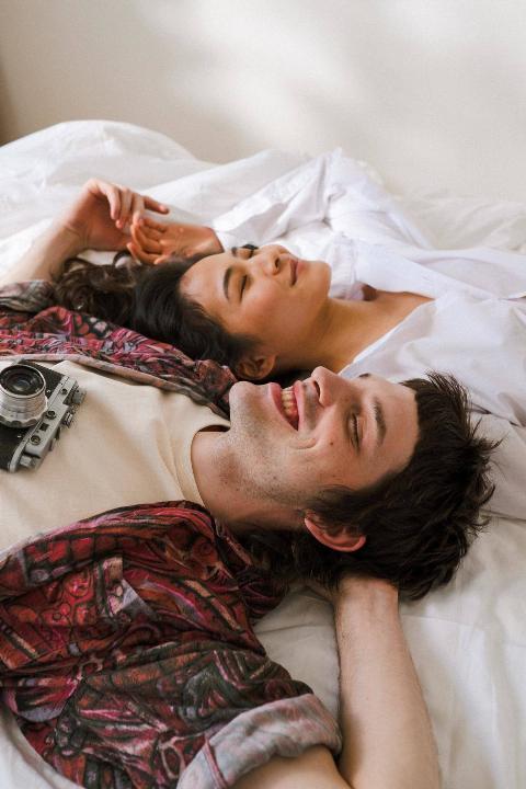 a-shot-of-a-couple-laying-on-a-bed-and-smiling-