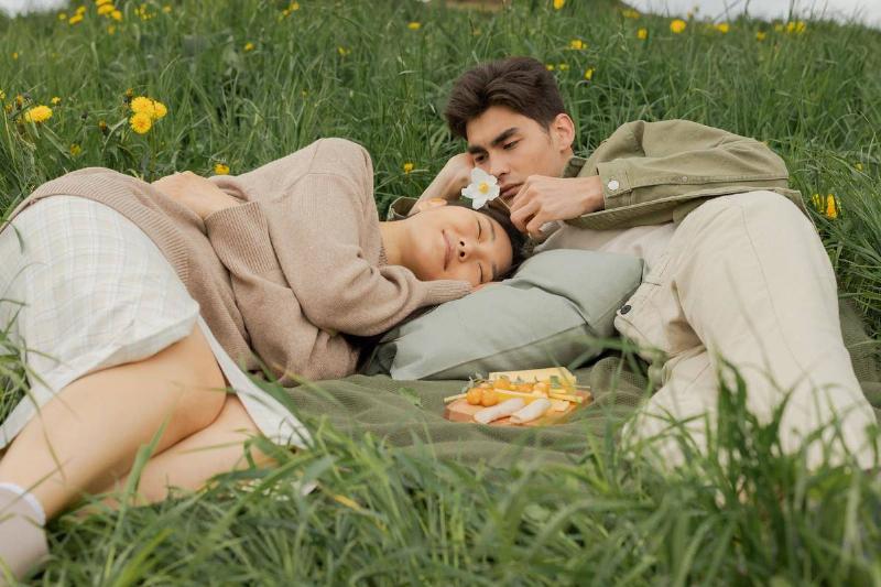 couple lays in grass cuddling