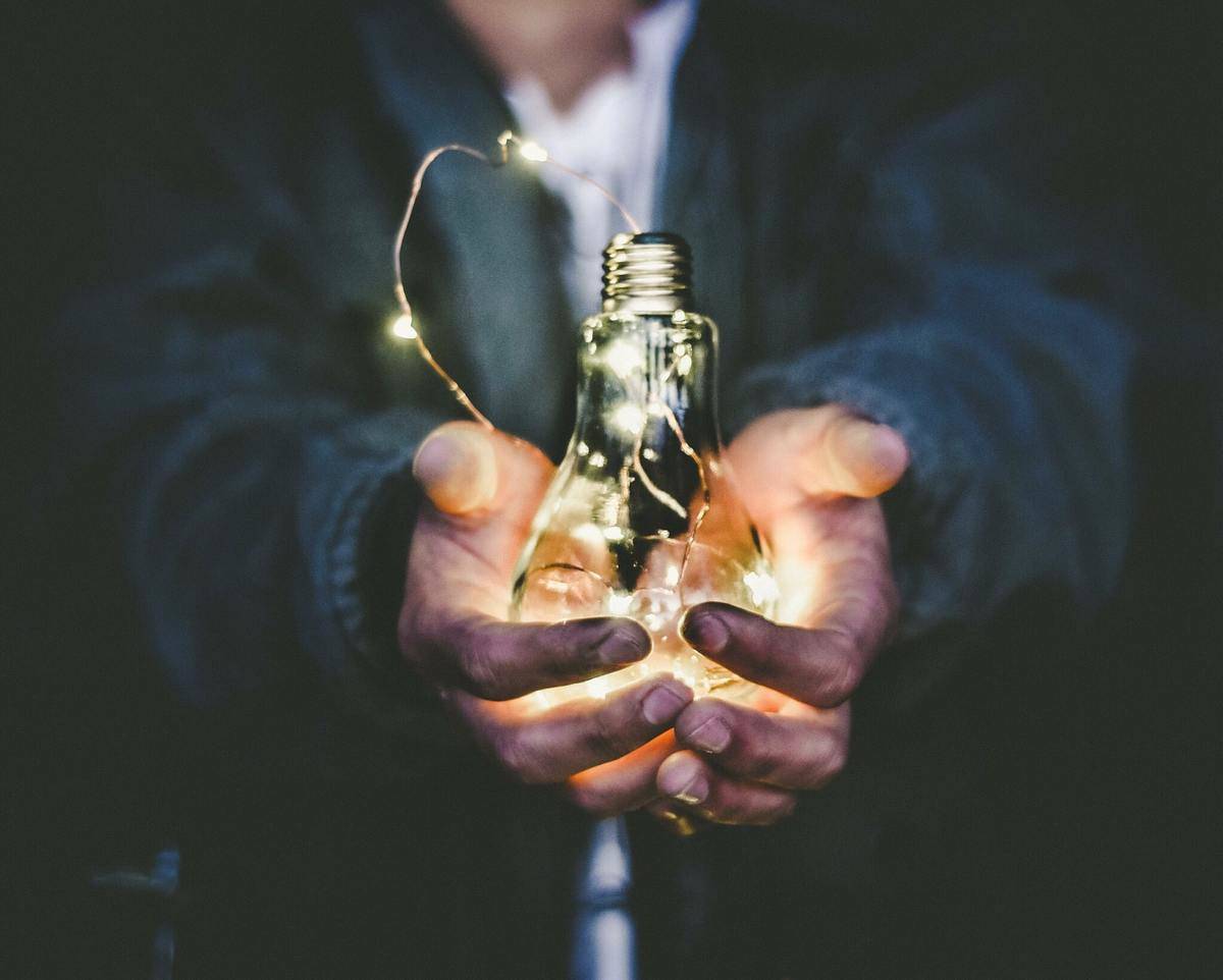 hand holding lightbulb with string lights