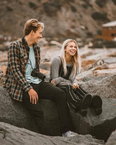 man-and-woman-sitting-on-a-rock laughing