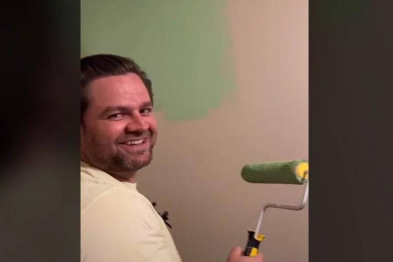 man painting wall green and smilling