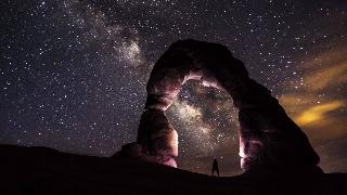 person-standing-under-a-rock-formation-on-a-starry-night