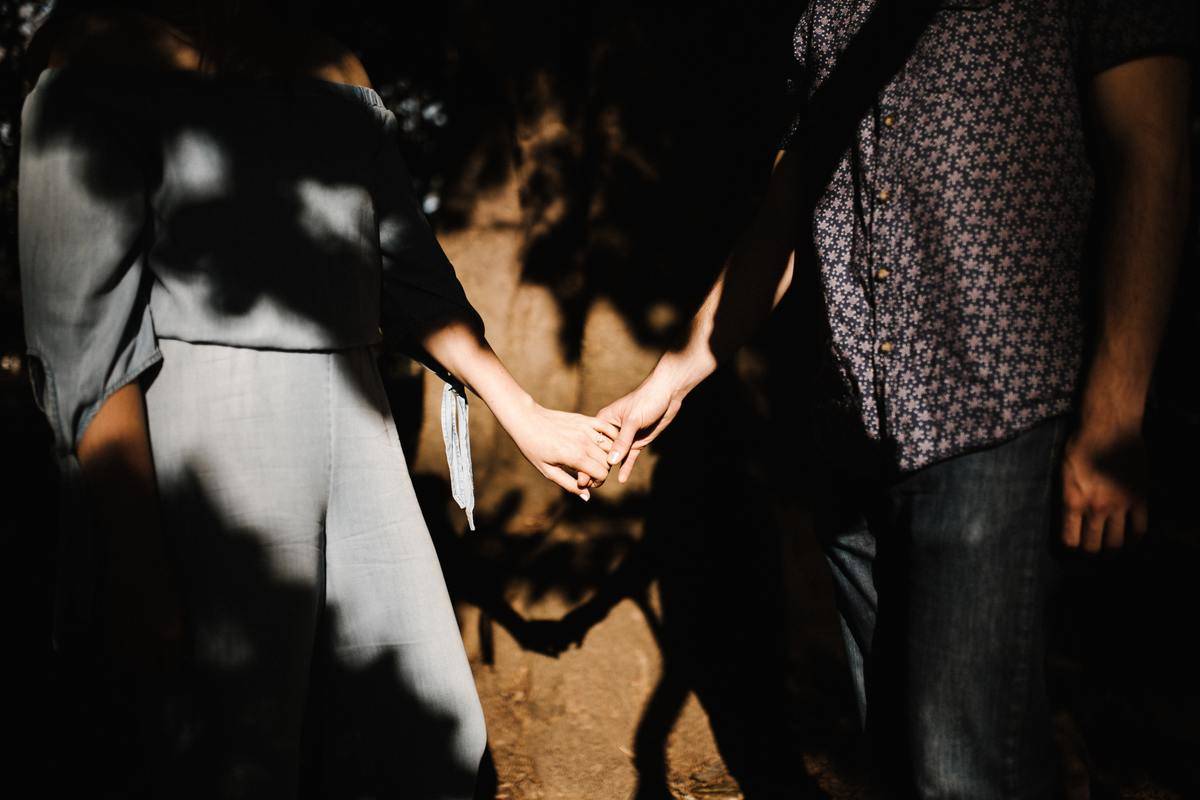  couple holding hands by wall in the shadows