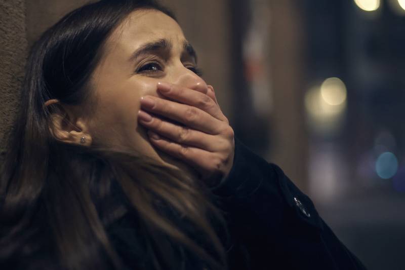 woman crying in alley with her hand over her mouth