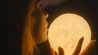 woman holding  full moon shape to her face