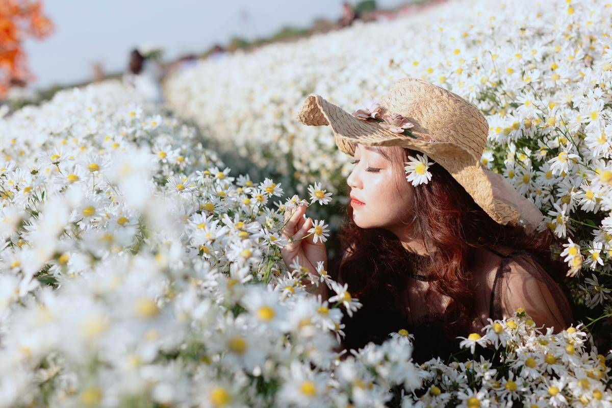 woman-with-a-hat-smelling-white-flowers