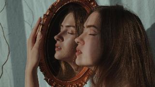a-woman-holding-a-mirror- and hugging it to her face with her eyes closed