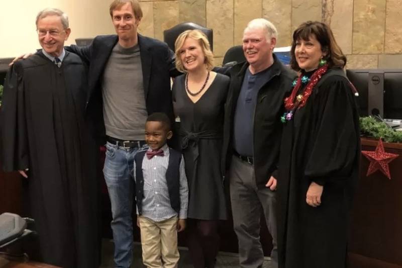 The little boy with his new family posing with judge