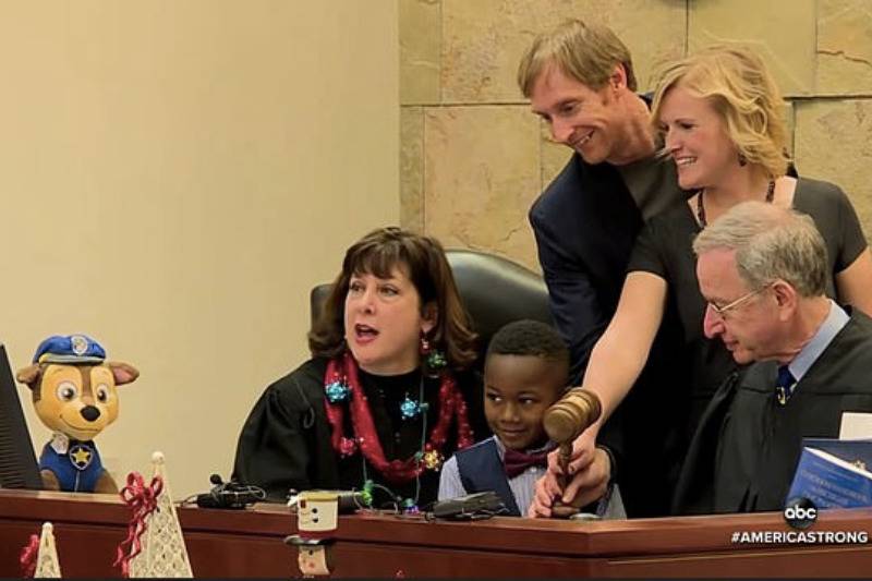 The hearing finalized the adoption of the five-year-old boy (center) by foster parents Andrea Melvin and Dave Eaton (standing)