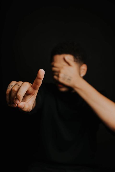 a-person-pointing-fingers-while-covering-his-eyes on dark background