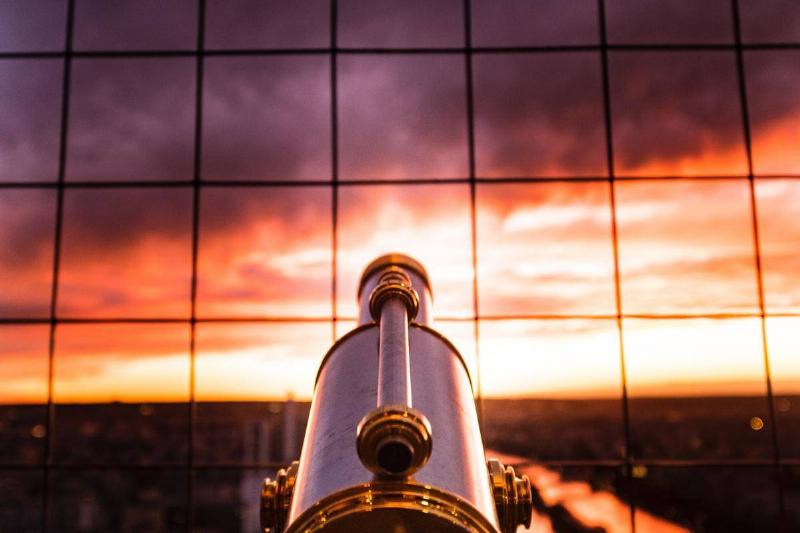 Telescope pointing to sunset in window