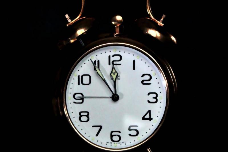 old school clock on black background shows 11:55